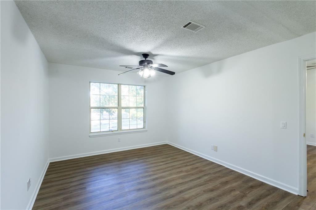 4908 Tarleton Drive Southwest Lilburn, GA 30047 - Photo 14 of 41 an empty room with wooden floor fan and windows