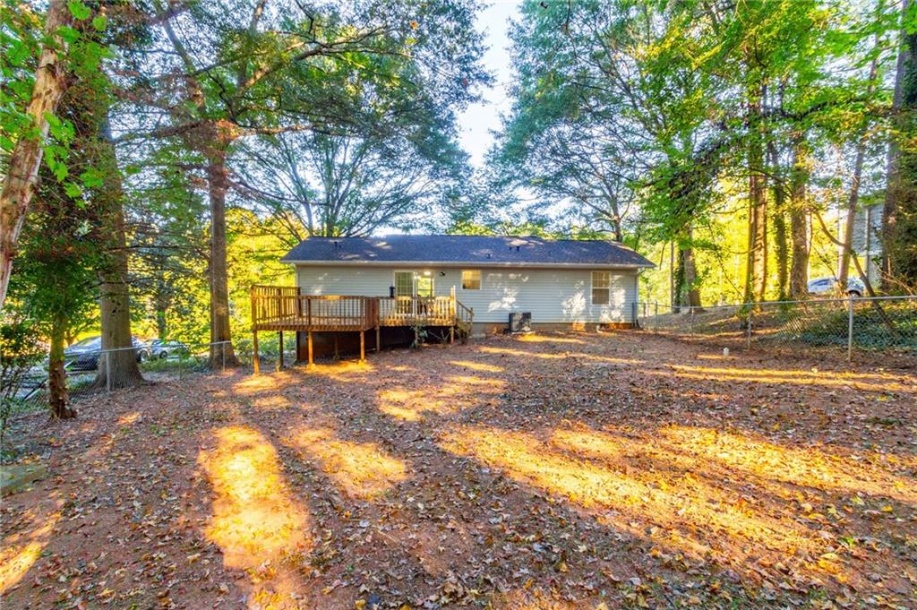 4908 Tarleton Drive Southwest Lilburn, GA 30047 - Photo 28 of 41 a view of a house with large trees and a big yard