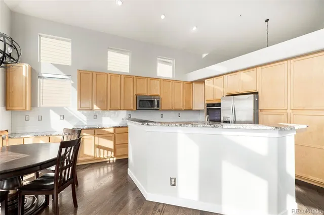 a kitchen with kitchen island a stove a sink a dining table and chairs