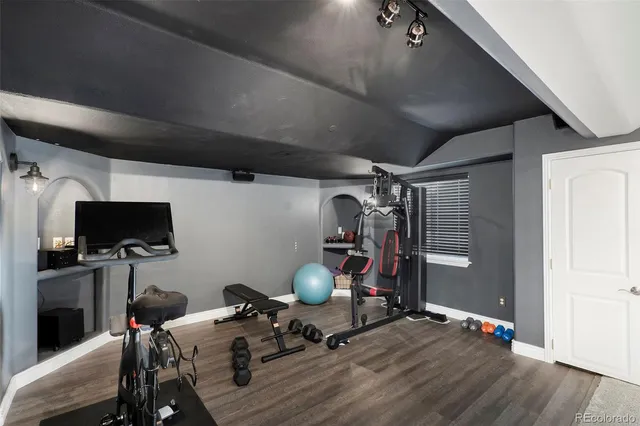 a room with gym equipment and wooden floor