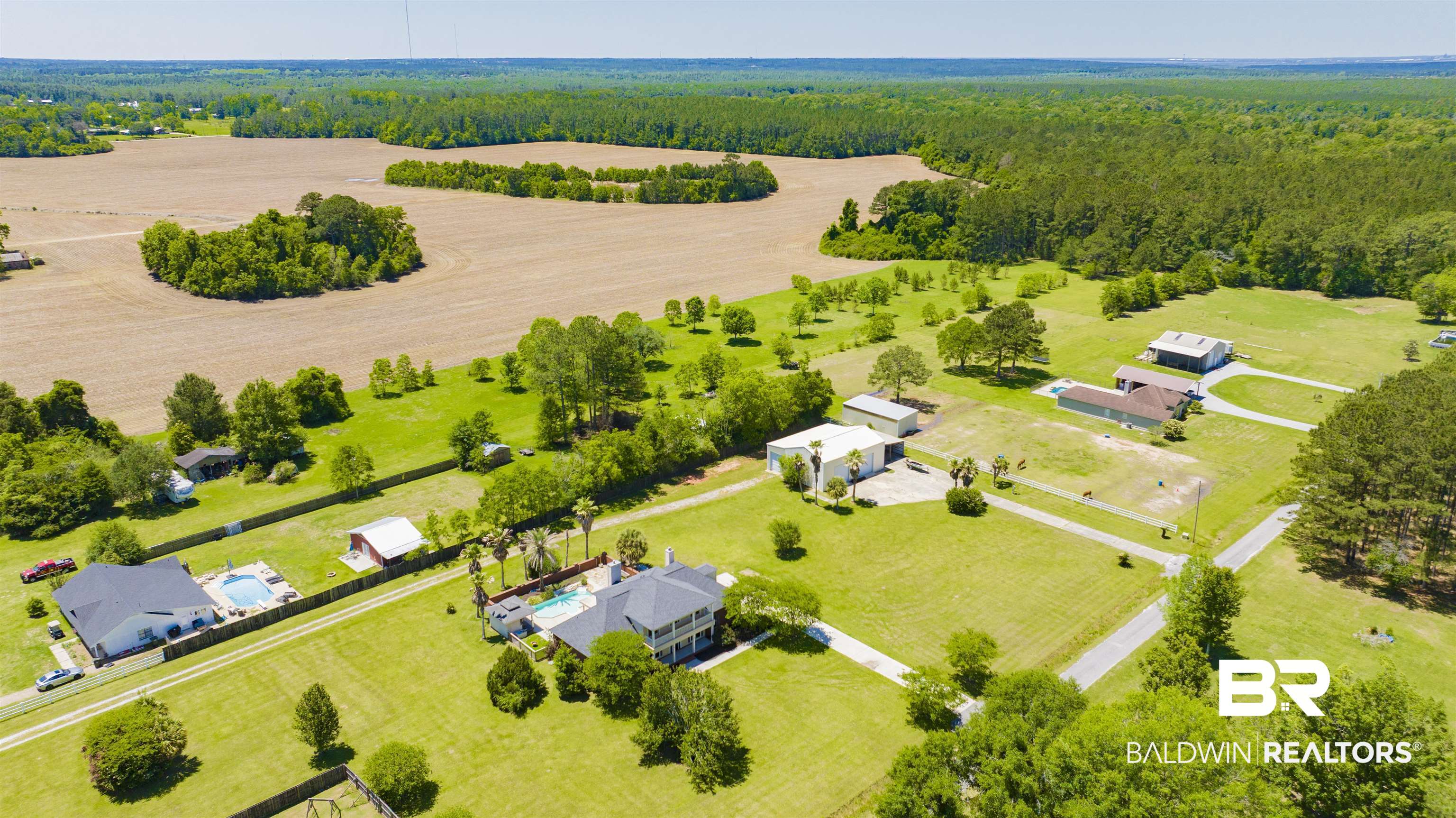12944 Anna's Way Stapleton, AL 36578 - Photo 5 of 64 Expansive rural property featuring multiple residential structures, two swimming pools, paved driveways, and surrounding agricultural fields
