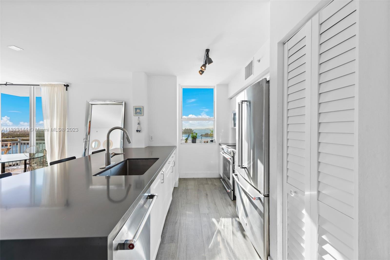 90 Alton Road, Unit 1602 Miami Beach, FL 33139 - Photo 11 of 34 a kitchen with granite countertop a refrigerator a sink a stove and white cabinets with wooden floor