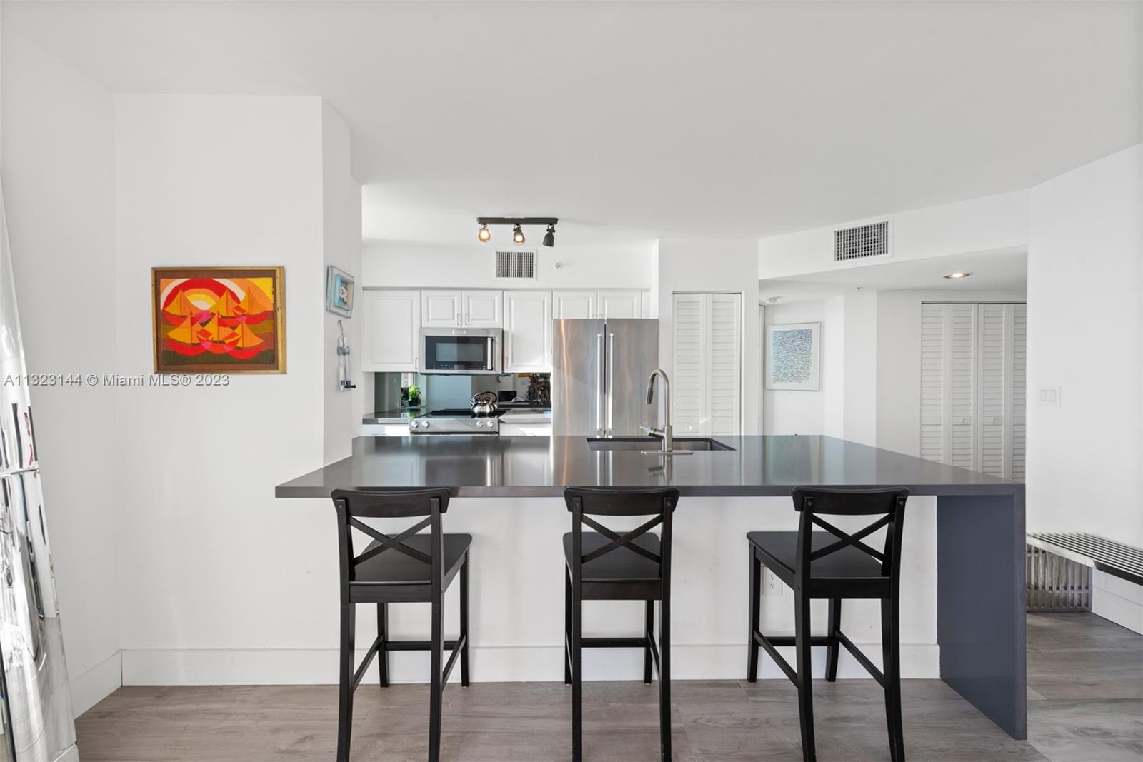 90 Alton Road, Unit 1602 Miami Beach, FL 33139 - Photo 13 of 34 a kitchen with stainless steel appliances kitchen island granite countertop a dining table chairs and a refrigerator