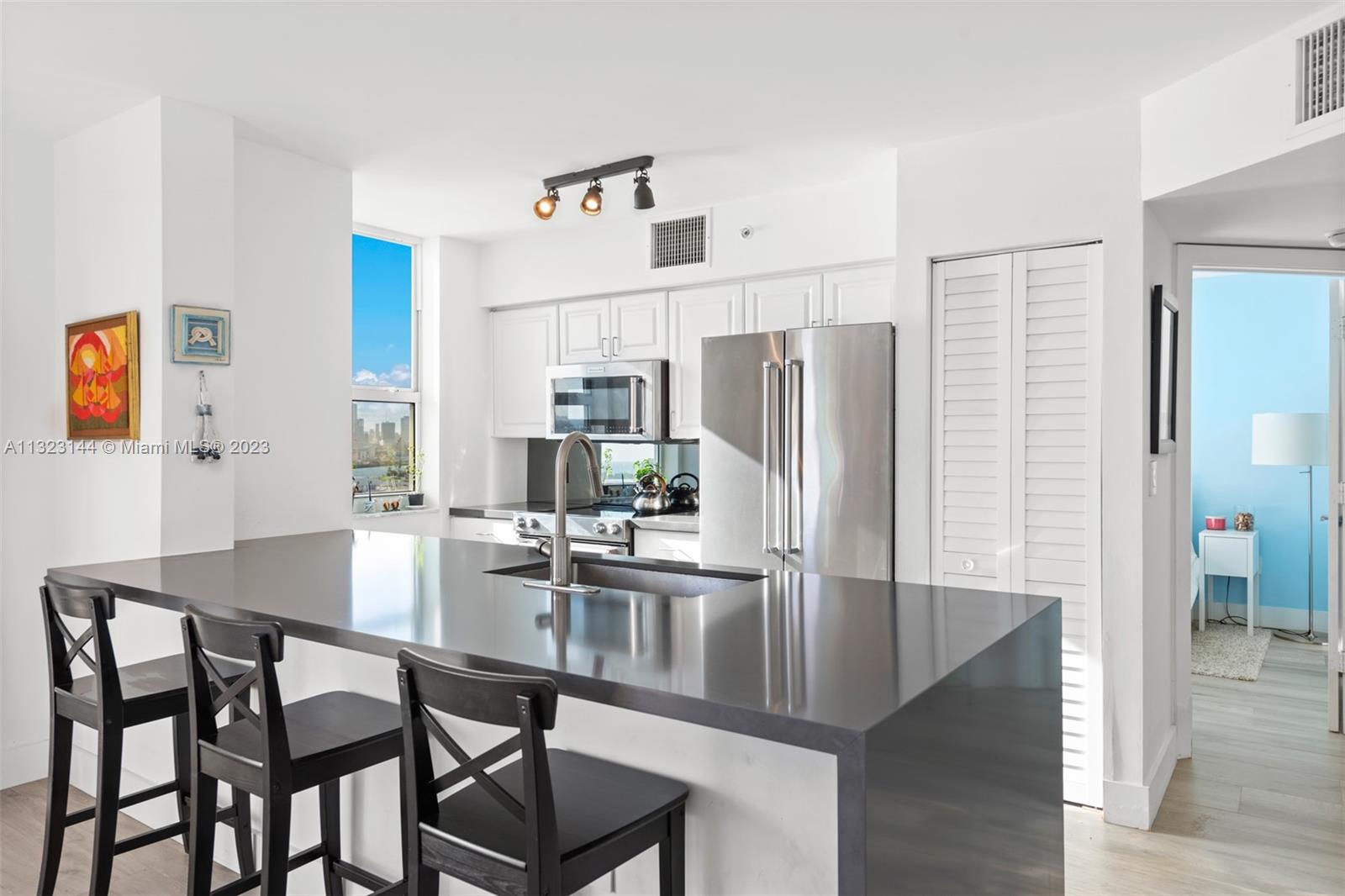 90 Alton Road, Unit 1602 Miami Beach, FL 33139 - Photo 10 of 34 a kitchen with stainless steel appliances a dining table chairs and refrigerator