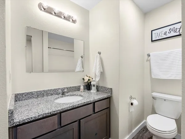 a bathroom with a granite countertop sink a toilet and a mirror