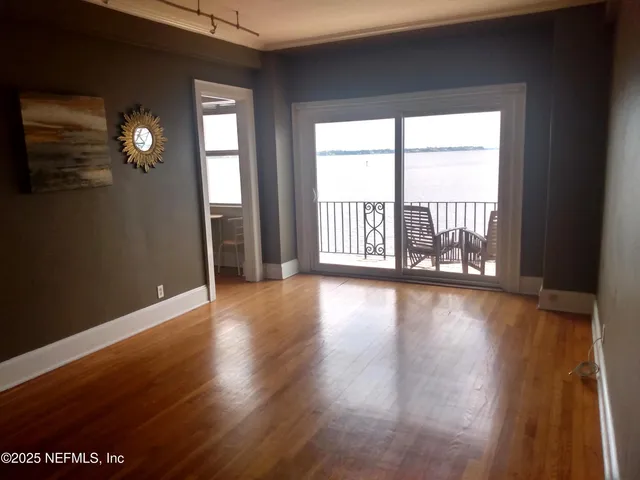a view of an empty room with wooden floor and a window