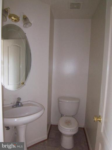 10102 Summershade Lane Springdale, MD 20721 - Photo 7 of 12 a bathroom with a toilet a sink and a mirror