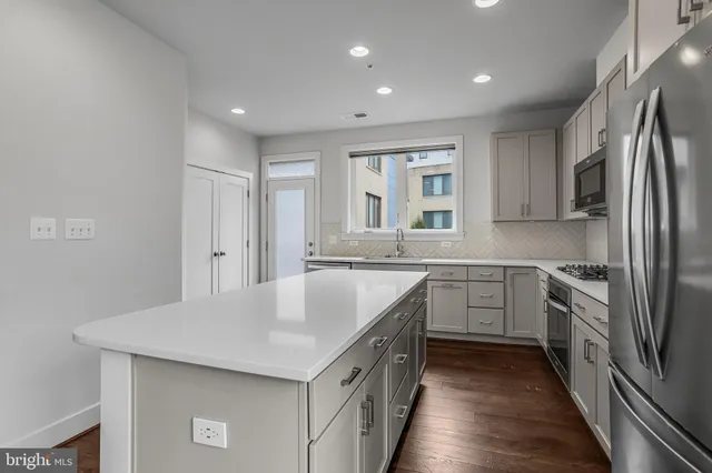 a kitchen with stainless steel appliances granite countertop a sink a stove a refrigerator and cabinets