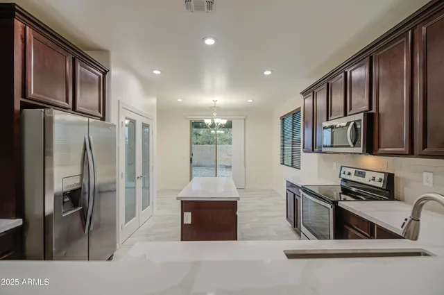 a kitchen with stainless steel appliances granite countertop a refrigerator a stove and a sink with wooden floor