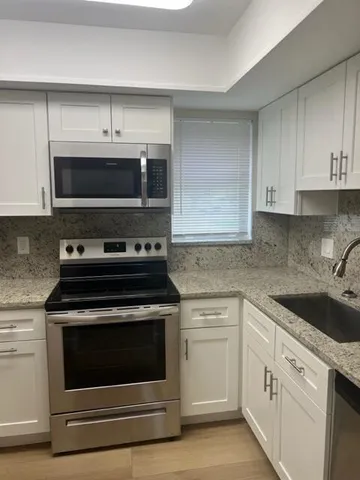 a kitchen with cabinets stainless steel appliances and a sink