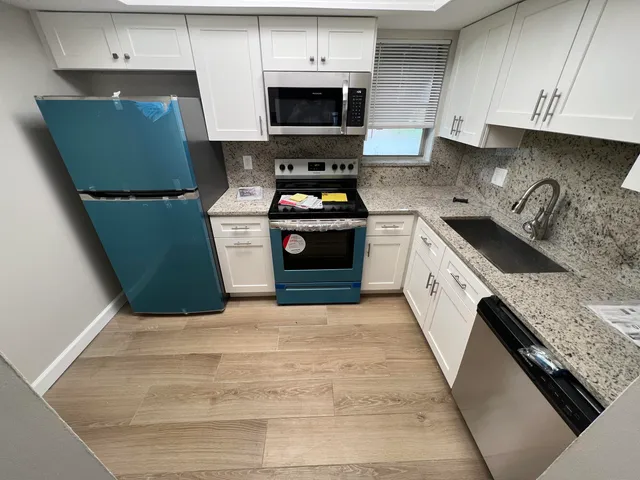 a kitchen with granite countertop a sink dishwasher stove and cabinets