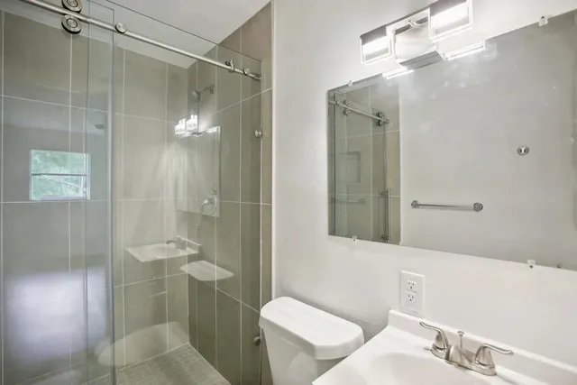 a bathroom with a shower a sink and toilet