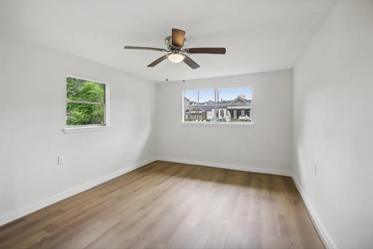 906 S Road Baytown, TX 77521 - Photo 15 of 32 an empty room with wooden floor ceiling fan and windows