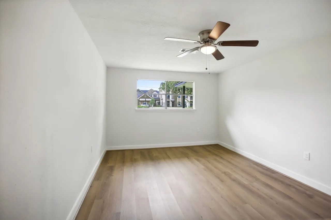 906 S Road Baytown, TX 77521 - Photo 17 of 32 an empty room with wooden floor ceiling fan and windows