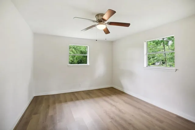 an empty room with wooden floor and windows