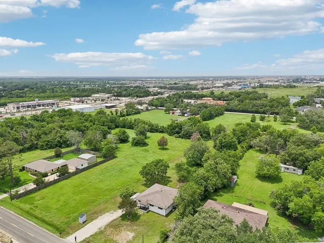 an aerial view of residential houses with outdoor space and trees