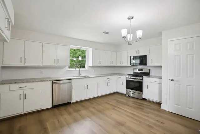 a kitchen with granite countertop white cabinets and stainless steel appliances