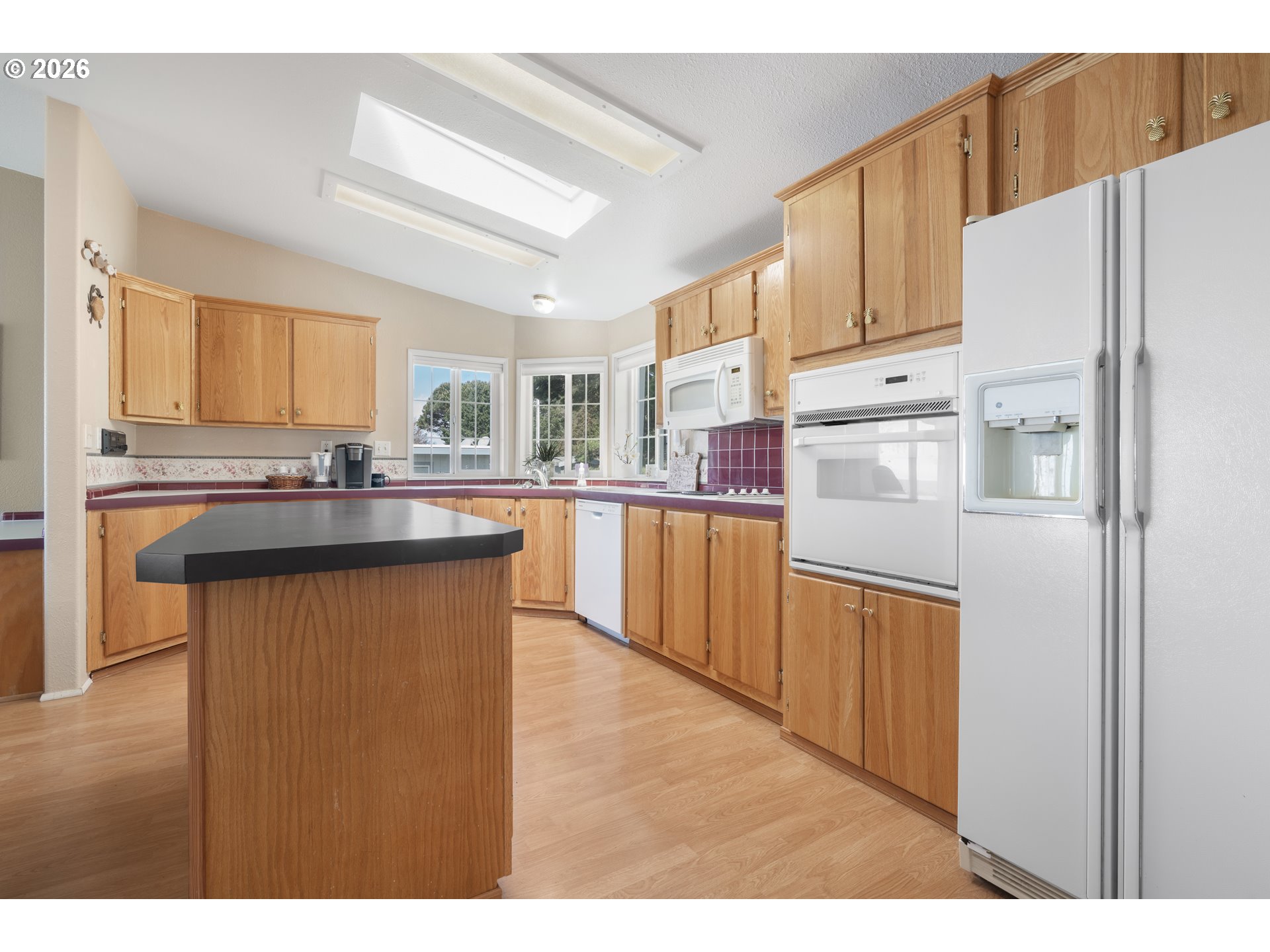 94033 Doyle Point Road Gold Beach, OR 97444 - Photo 14 of 42 a kitchen with stainless steel appliances kitchen island granite countertop a refrigerator a sink dishwasher and white cabinets with wooden floor