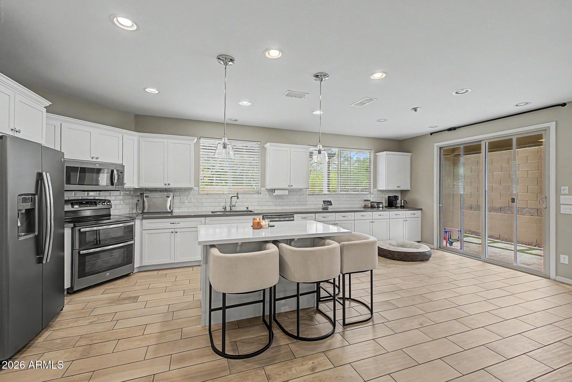 15918 South 11th Way Phoenix, AZ 85048 - Photo 7 of 32 a kitchen with stainless steel appliances kitchen island granite countertop a stove a sink a refrigerator a dining table and chairs