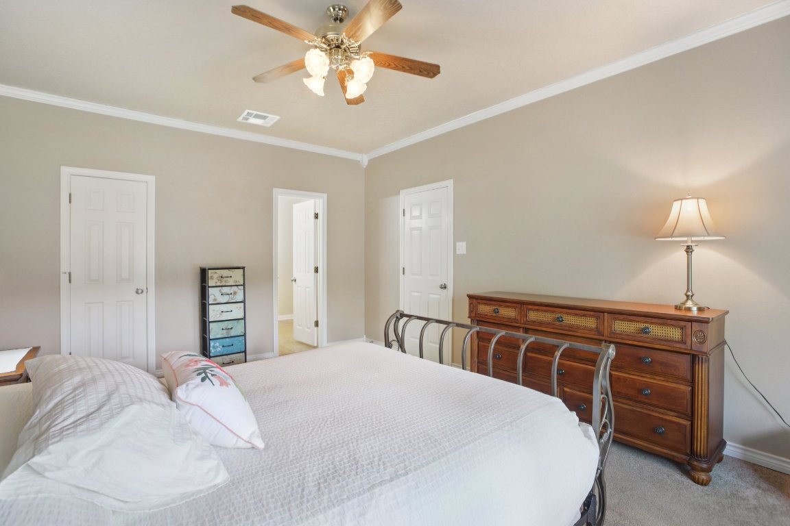 148 Oak Ridge Drive Cedar Creek, TX 78612 - Photo 26 of 40 a bedroom with a bed and a chandelier