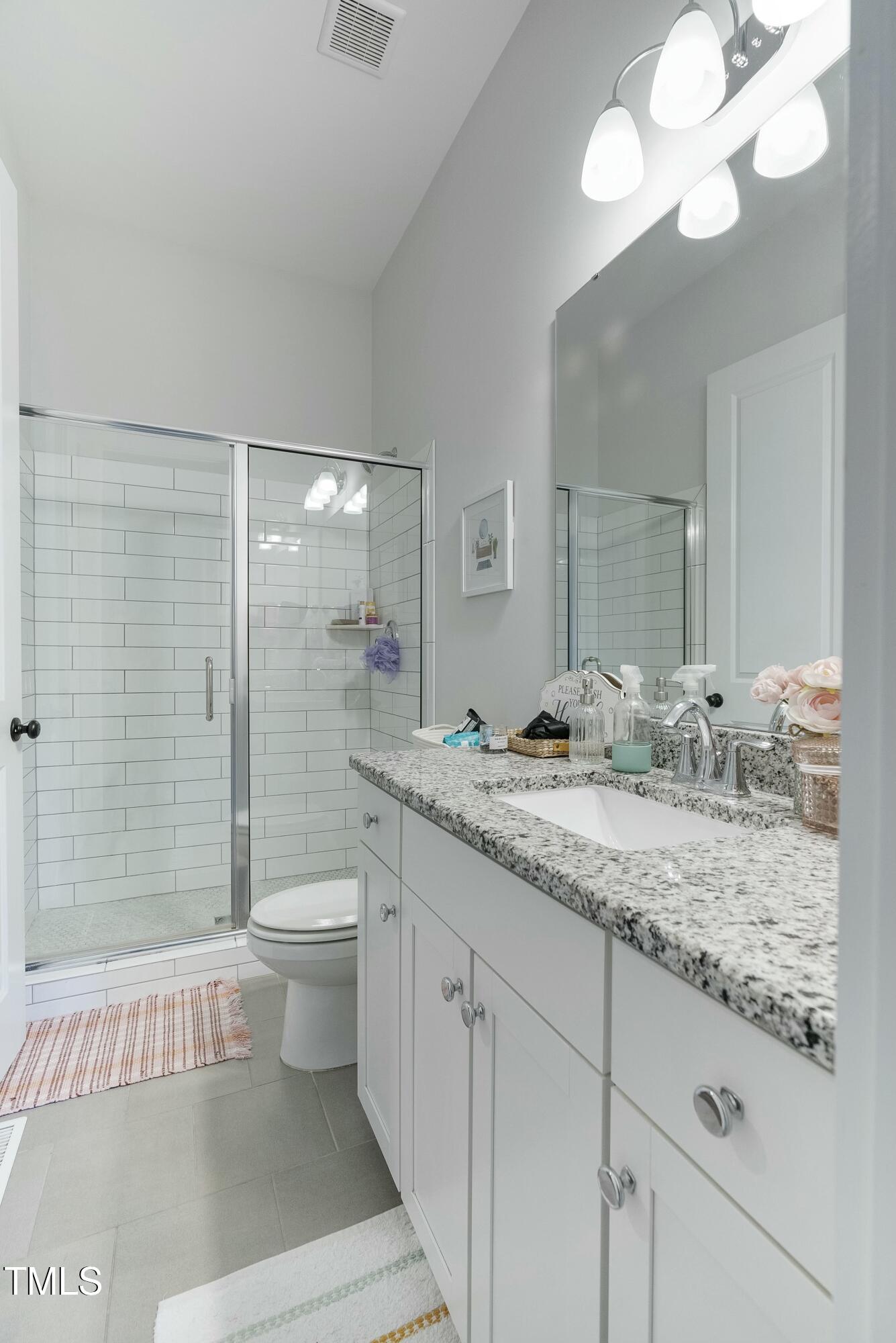 512 Adkins Ridge Road Rolesville, NC 27571 - Photo 14 of 53 a bathroom with a granite countertop sink a toilet a mirror and shower