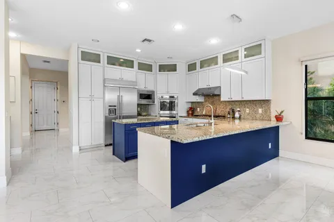 a kitchen with kitchen island granite countertop a sink refrigerator and cabinets