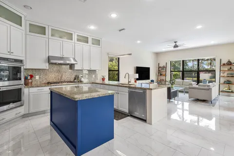 a kitchen with kitchen island granite countertop a stove sink and cabinets