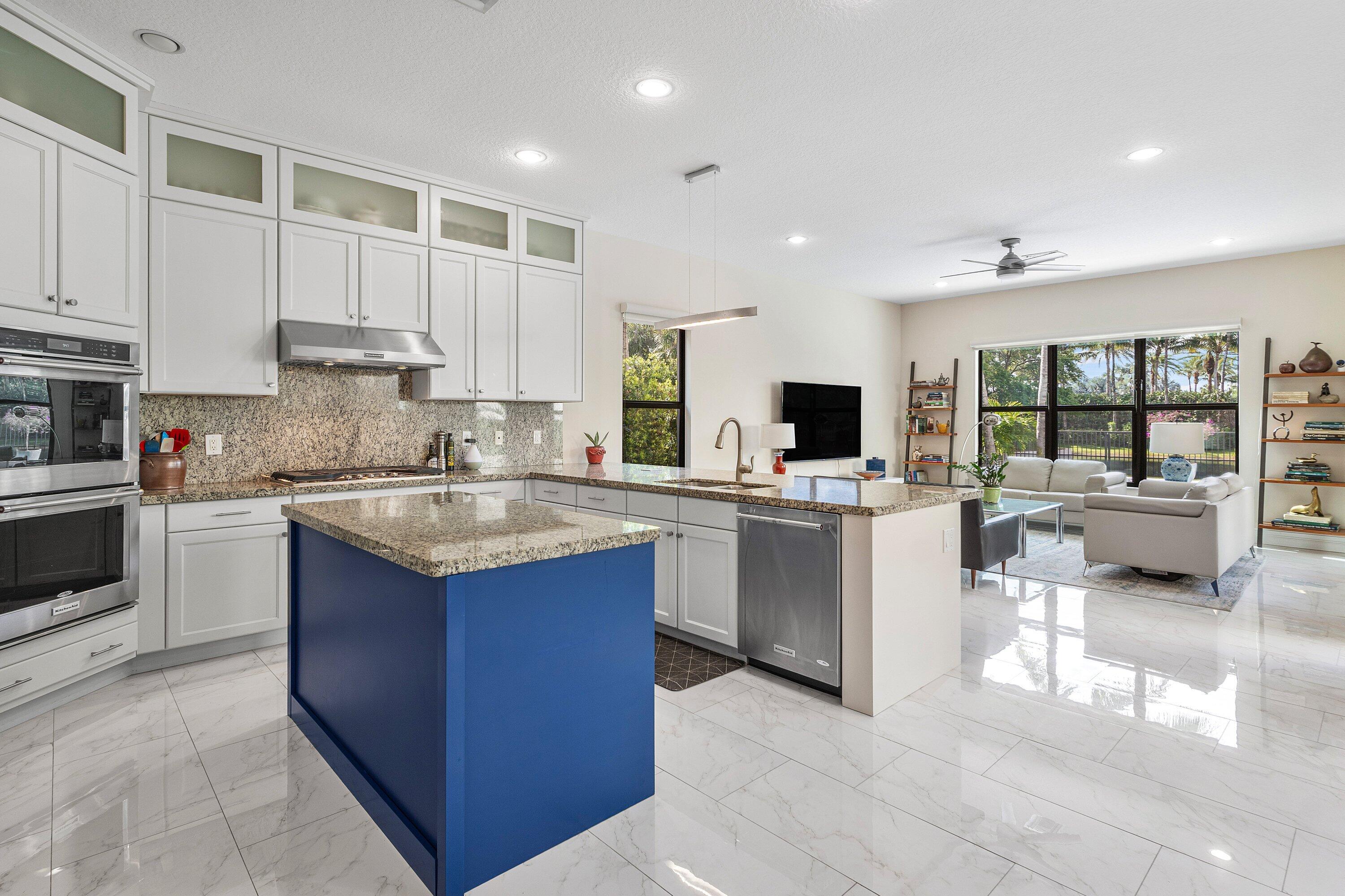 9349 Eden Roc Court Delray Beach, FL 33446 - Photo 9 of 50 a kitchen with kitchen island granite countertop a stove sink and cabinets