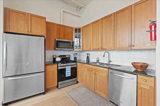 a kitchen with stainless steel appliances granite countertop a sink a stove and cabinets