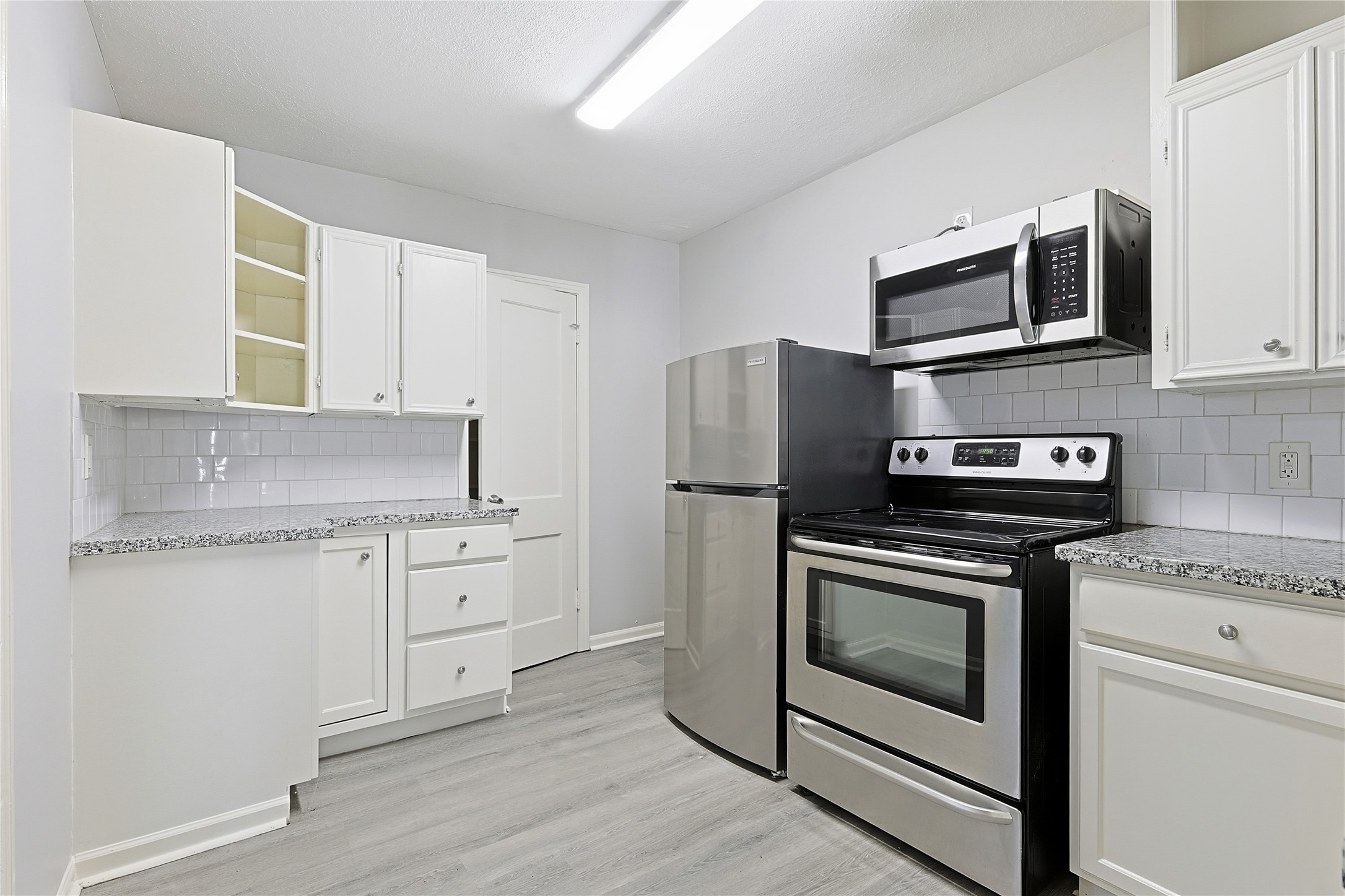 207 Farrer Street Angleton, TX 77515 - Photo 22 of 24 a kitchen with stainless steel appliances granite countertop a stove microwave and refrigerator