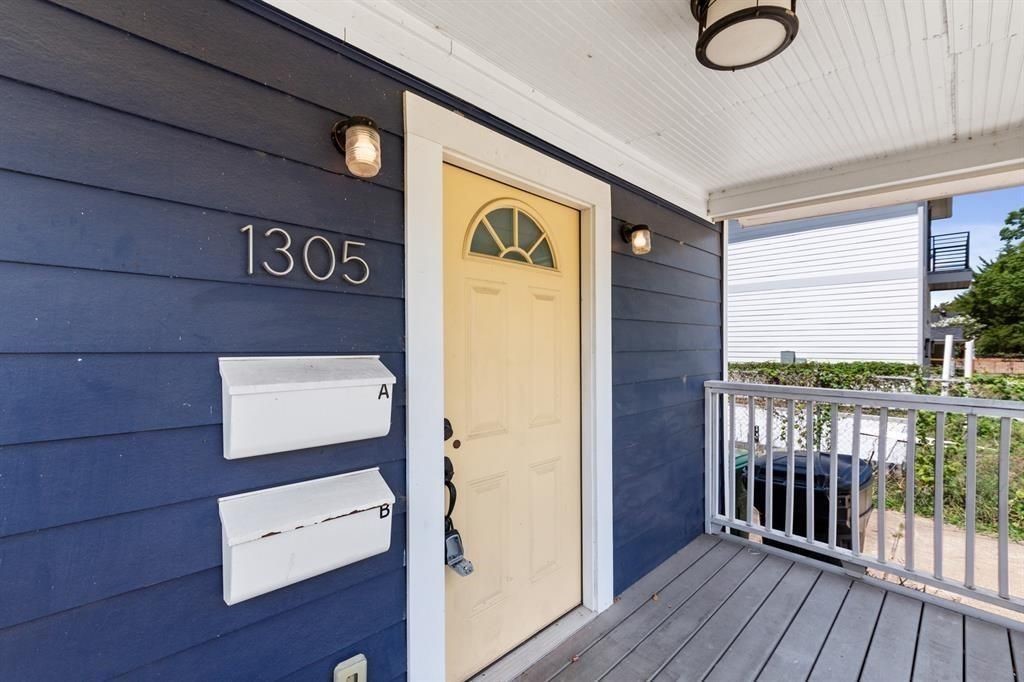 1305 Idylwild Street Houston, TX 77009 - Photo 4 of 31 Charming front porch with blue siding features a welcoming yellow door, dual mailboxes, and modern lighting. Ideal for a cozy entryway.