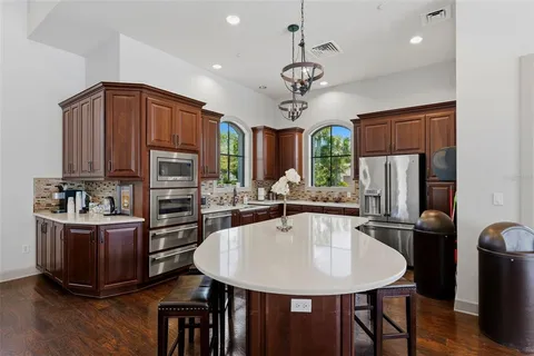 a kitchen with stainless steel appliances kitchen island granite countertop a refrigerator a stove a sink dishwasher and wooden cabinets with wooden floor