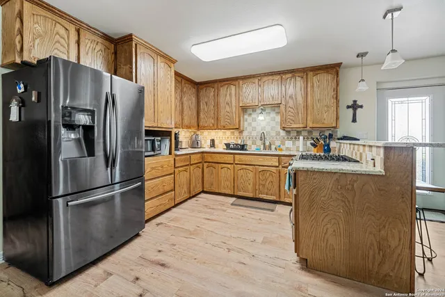 a kitchen with stainless steel appliances granite countertop a refrigerator a sink dishwasher a stove and a refrigerator