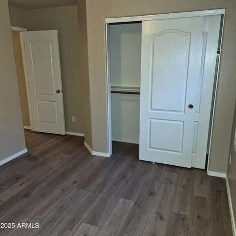 an empty room with wooden floor and closet area