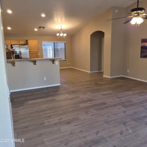 a view of kitchen and empty room with wooden floor