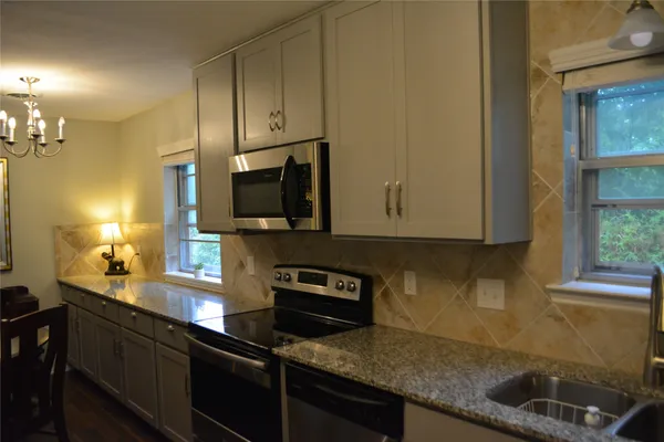 a kitchen with granite countertop a sink a stove cabinets and black appliances