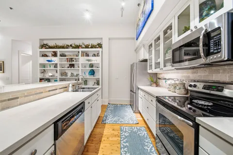 a kitchen with stainless steel appliances a stove a sink and a white cabinets