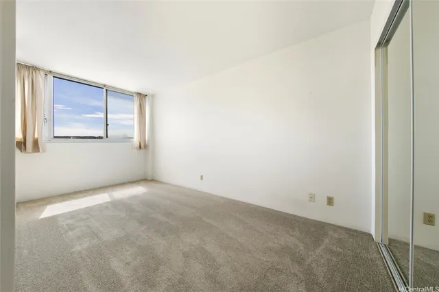 a view of an empty room with closet and a window