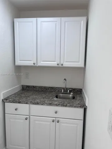 a kitchen with granite countertop white cabinets and a sink