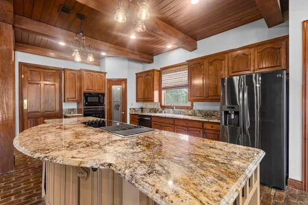 a kitchen with stainless steel appliances kitchen island granite countertop a refrigerator and a stove top oven