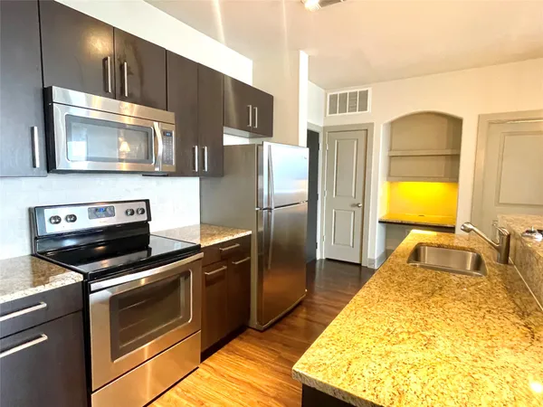 a kitchen with stainless steel appliances granite countertop a refrigerator and a stove top oven
