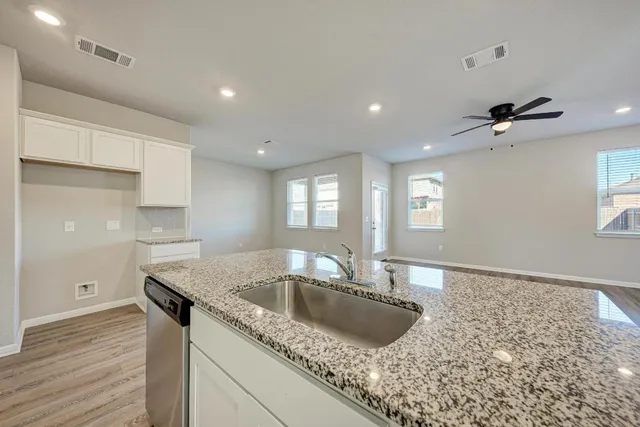 a kitchen with granite countertop a sink and wooden floor