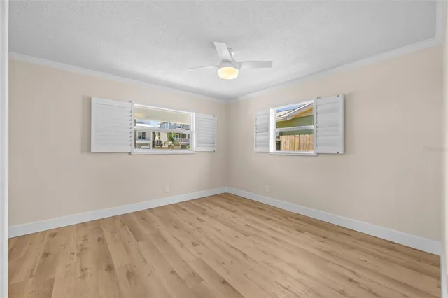a view of empty room with wooden floor and fan