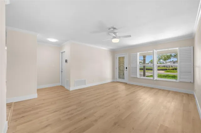 a view of an empty room with a window and wooden floor
