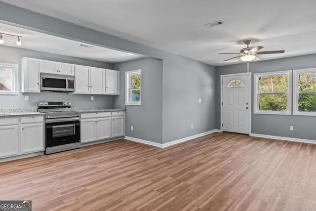 a kitchen with stainless steel appliances granite countertop a stove top oven a sink and white cabinets