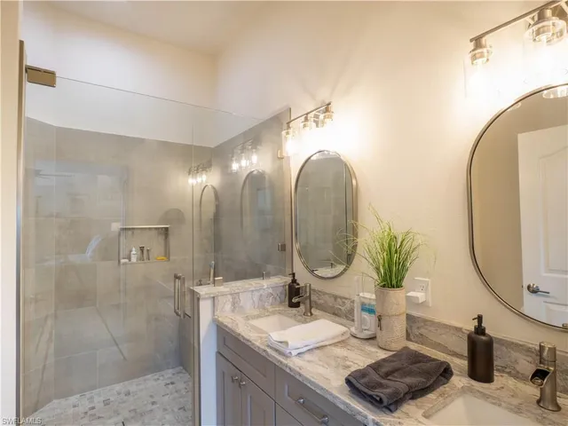 a bathroom with a granite countertop sink a mirror and shower