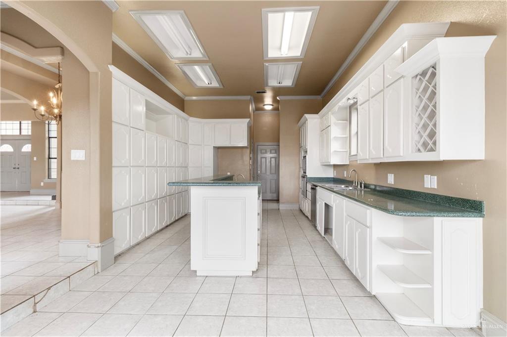 2107 South Victoria Road Donna, TX 78537 - Photo 4 of 25 Kitchen featuring open shelves, white cabinetry, ornamental molding, light tile patterned floors, and a center island with sink