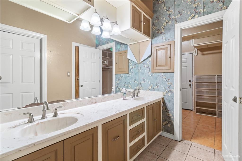 2107 South Victoria Road Donna, TX 78537 - Photo 7 of 25 Full bath featuring wallpapered walls, light tile patterned flooring, a spacious closet, and double vanity