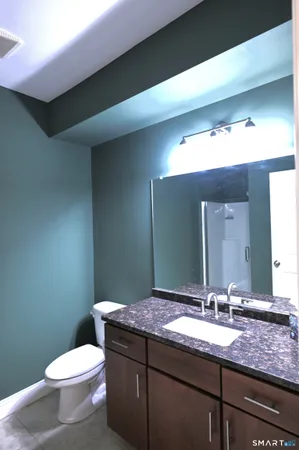 a bathroom with a granite countertop toilet sink and mirror