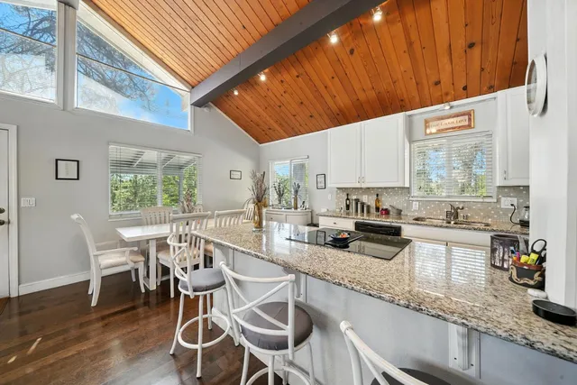 a kitchen with stainless steel appliances kitchen island granite countertop a table chairs in it and wooden floors